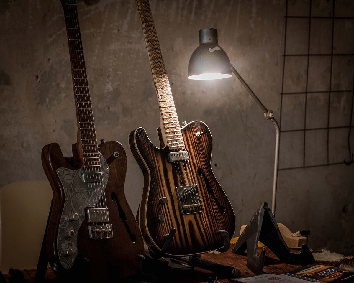 leisure activities two brown guitars beside desk lamp electric guitar